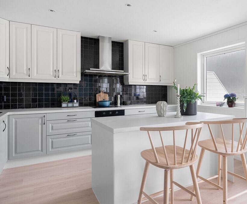 Kitchen with two-tone cabinetry and black backsplash