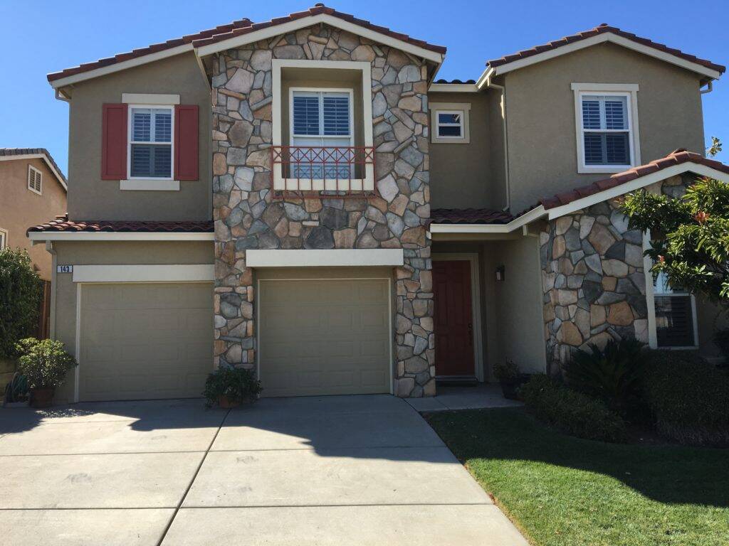 Exterior home painting project in Brentwood with flagstone facade, warm beige walls, white trim, and brick red accents