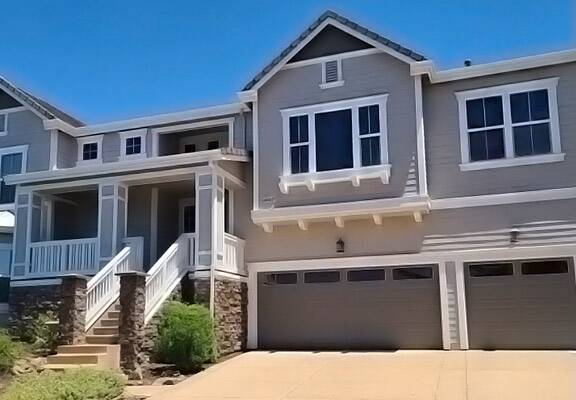Multi-family property with light blue-grey paint, white trim, and dark grey garage doors